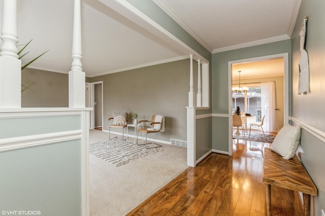 corridor with wood-type flooring, crown molding, and a chandelier