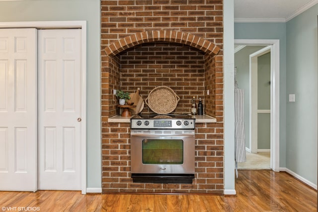 kitchen with crown molding, stainless steel stove, and wood-type flooring