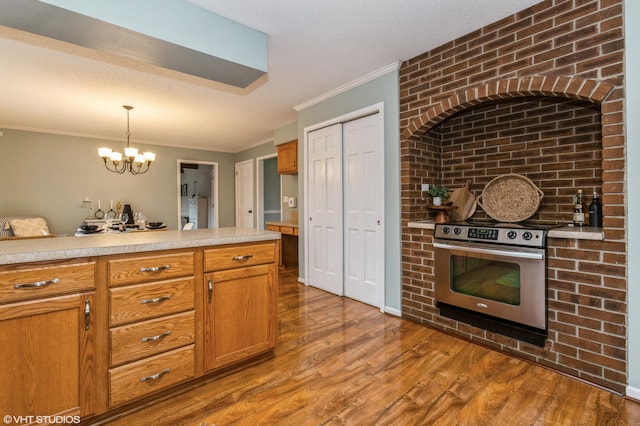 kitchen featuring crown molding, pendant lighting, electric range, hardwood / wood-style flooring, and a notable chandelier