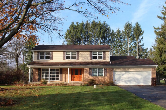 9370 Moon Rd, Saline, MI 48176 - traditional-style house featuring an attached garage, brick siding, driveway, and a front yard