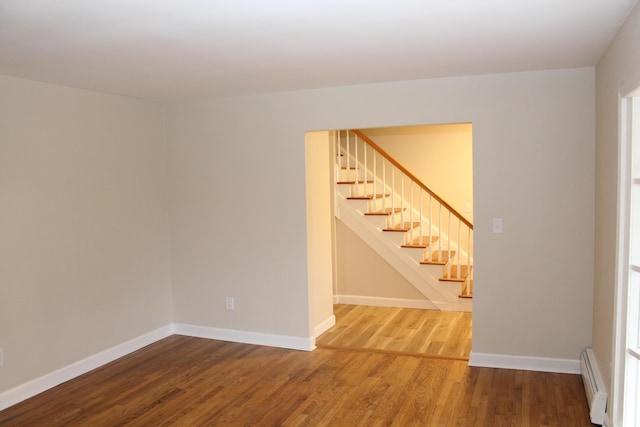 9370 Moon Rd, Saline, MI 48176 - spare room featuring a baseboard heating unit, wood finished floors, stairway, and baseboards