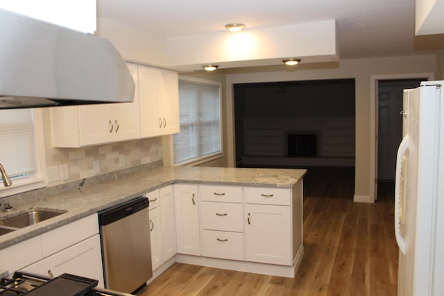 kitchen with stainless steel dishwasher, kitchen peninsula, white fridge, white cabinets, and exhaust hood