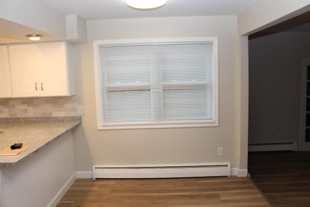 9370 Moon Rd, Saline, MI 48176 - unfurnished dining area featuring a baseboard heating unit, wood finished floors, and baseboards