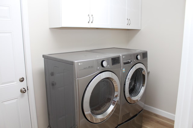 9370 Moon Rd, Saline, MI 48176 - washroom with washer and clothes dryer, light wood-type flooring, cabinet space, and baseboards