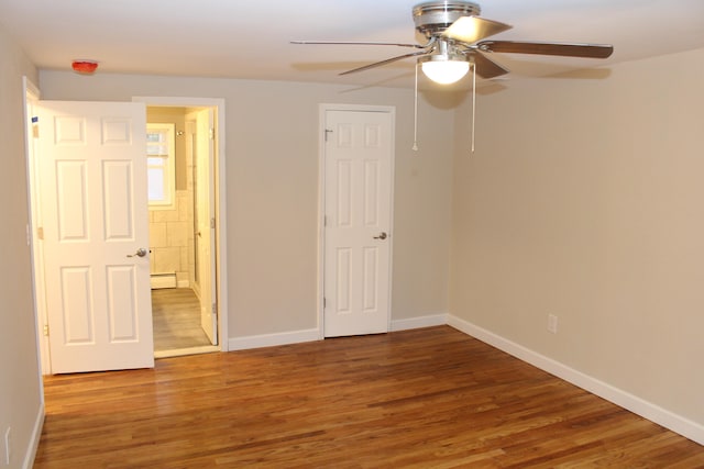 unfurnished bedroom with baseboard heating, ceiling fan, and hardwood / wood-style floors