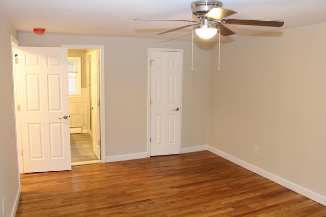 9370 Moon Rd, Saline, MI 48176 - unfurnished bedroom featuring wood finished floors, baseboard heating, baseboards, and a ceiling fan