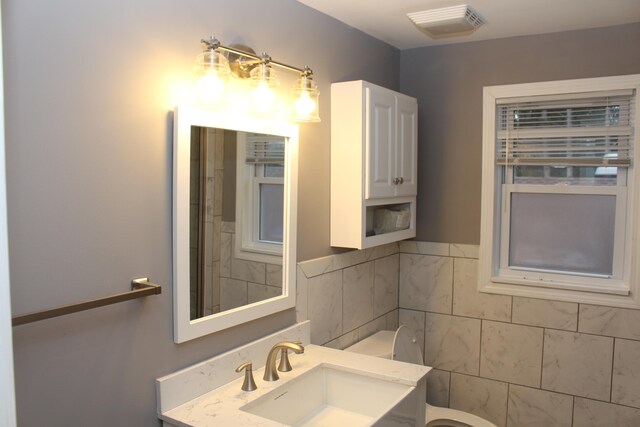 bathroom featuring vanity, tile walls, and toilet