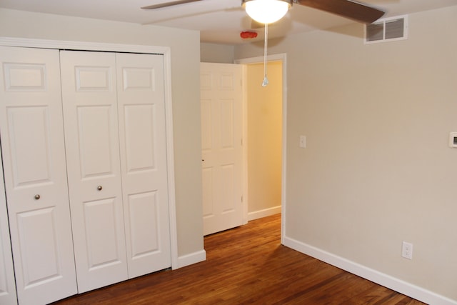 unfurnished bedroom with ceiling fan, dark wood-type flooring, and a closet