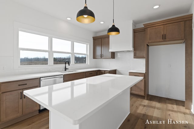 kitchen with a center island, light hardwood / wood-style floors, sink, and hanging light fixtures