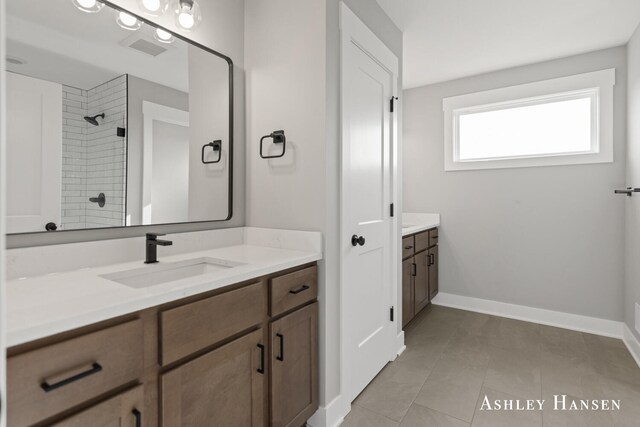 bathroom featuring a tile shower, vanity, and tile patterned floors