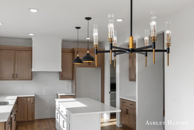 kitchen with pendant lighting, a kitchen island, wood-type flooring, and sink