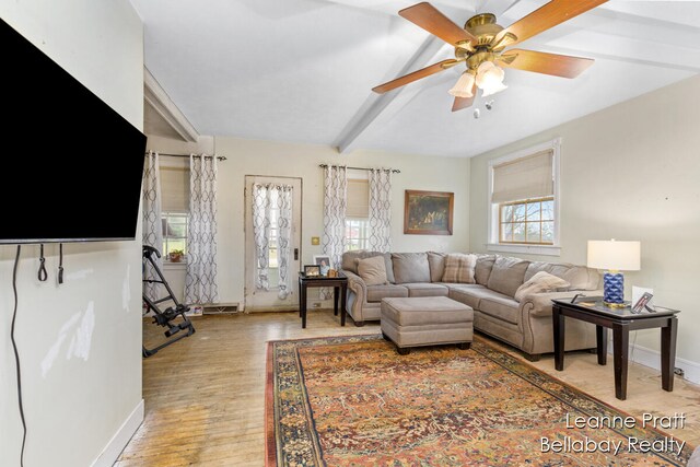 living room with ceiling fan, light hardwood / wood-style flooring, and beamed ceiling