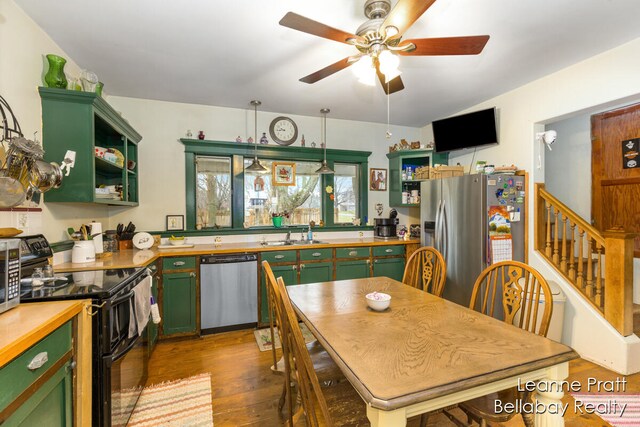 kitchen featuring decorative light fixtures, green cabinets, dark wood-type flooring, and appliances with stainless steel finishes