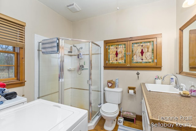 bathroom featuring hardwood / wood-style flooring, vanity, a shower with door, and washer / clothes dryer