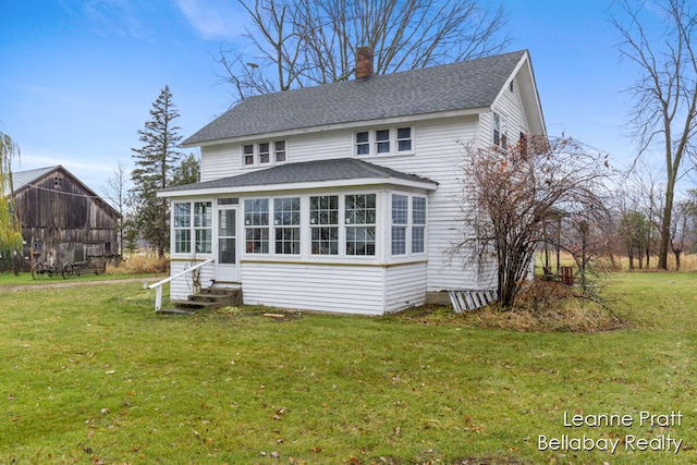 back of house featuring a lawn and a sunroom