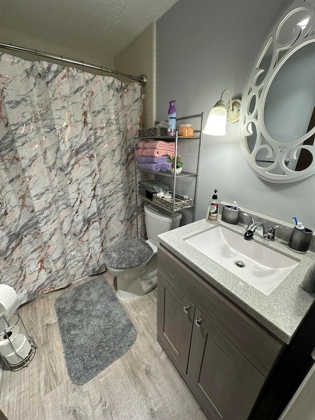 bathroom featuring vanity, wood-type flooring, a textured ceiling, and toilet