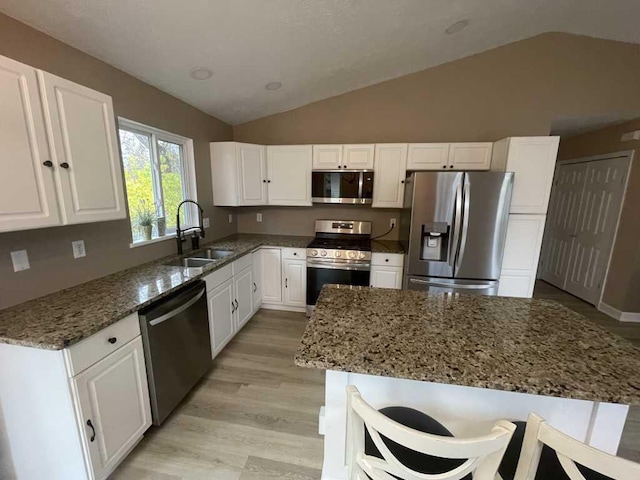 kitchen featuring sink, white cabinetry, stainless steel appliances, and vaulted ceiling