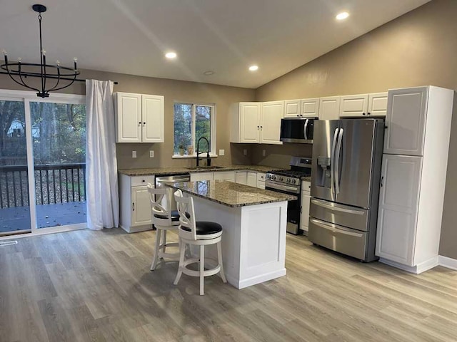 kitchen featuring a center island, sink, dark stone countertops, a notable chandelier, and stainless steel appliances