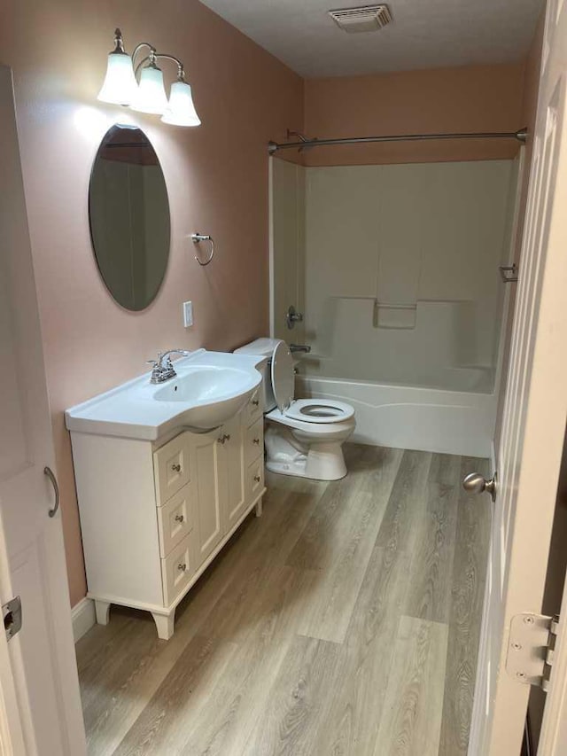 full bathroom with shower / tub combination, vanity, hardwood / wood-style flooring, and toilet