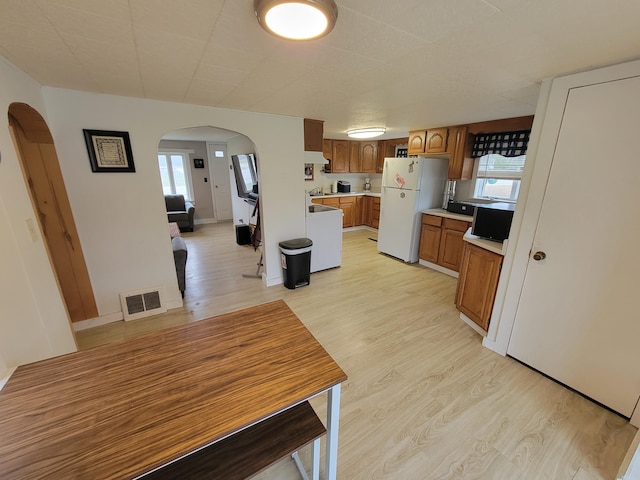 kitchen with white fridge, light hardwood / wood-style flooring, plenty of natural light, and range hood