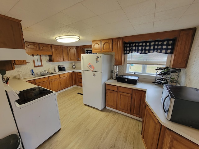 kitchen with sink, extractor fan, white appliances, decorative backsplash, and light wood-type flooring