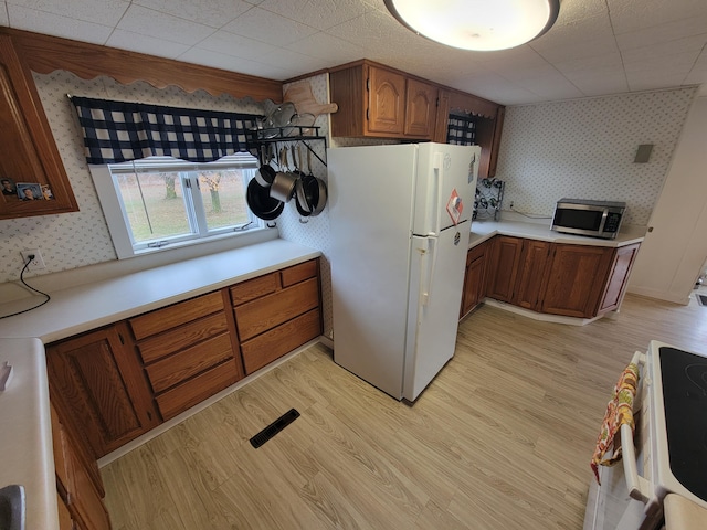 kitchen featuring range, light wood-type flooring, and white fridge