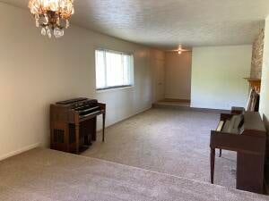 unfurnished living room featuring light carpet, a textured ceiling, and a notable chandelier