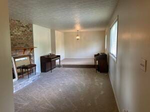 unfurnished living room featuring a fireplace, a textured ceiling, and carpet floors