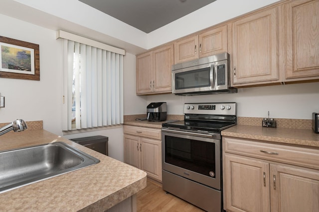 kitchen featuring light brown cabinetry, sink, appliances with stainless steel finishes, and light hardwood / wood-style flooring