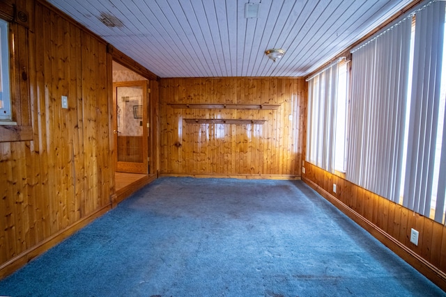 empty room featuring wooden ceiling, wood walls, and dark colored carpet