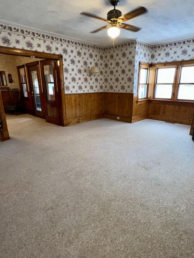 carpeted empty room featuring ceiling fan, crown molding, and a textured ceiling