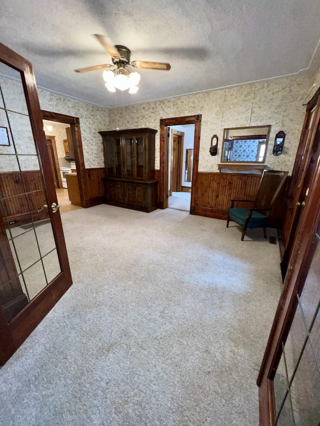 interior space featuring a textured ceiling, ceiling fan, and wooden walls