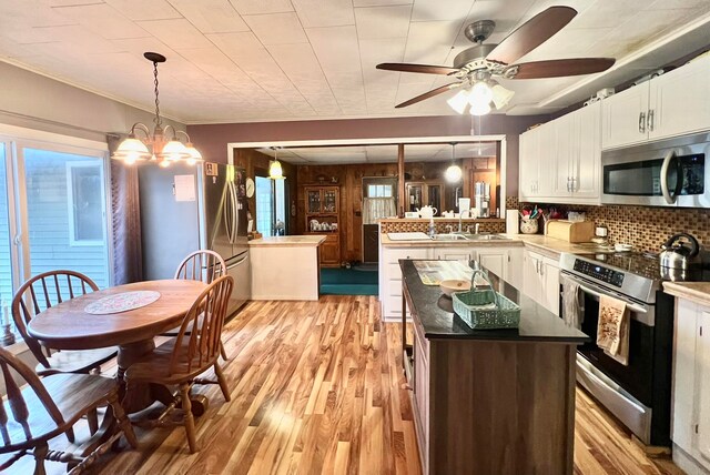 kitchen with a center island, decorative backsplash, appliances with stainless steel finishes, light hardwood / wood-style floors, and white cabinetry