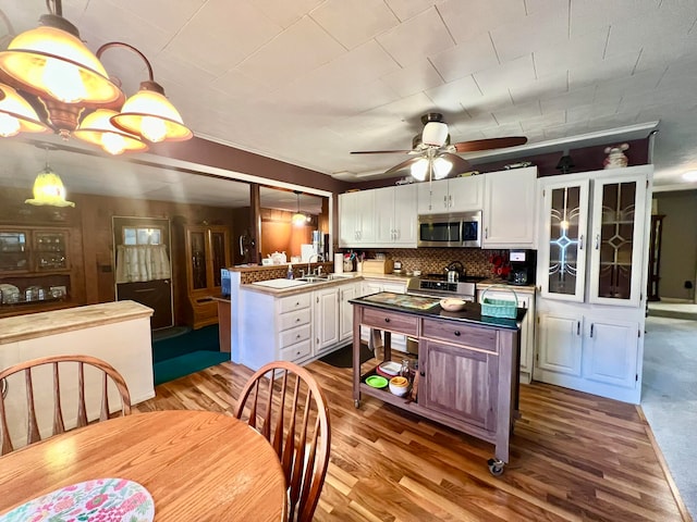 kitchen with backsplash, sink, light hardwood / wood-style floors, white cabinetry, and hanging light fixtures