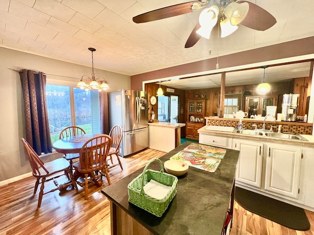 dining area featuring ceiling fan with notable chandelier, light hardwood / wood-style floors, ornamental molding, and sink