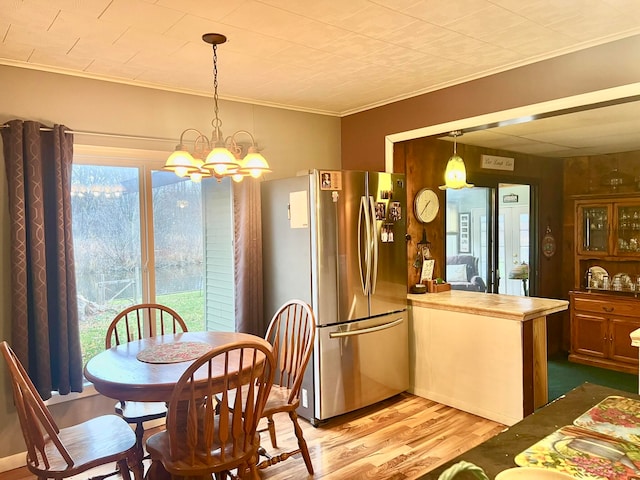 dining area featuring crown molding, light hardwood / wood-style floors, and an inviting chandelier