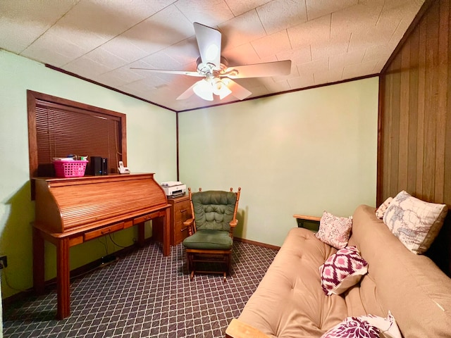 sitting room featuring ceiling fan, wood walls, carpet floors, and crown molding