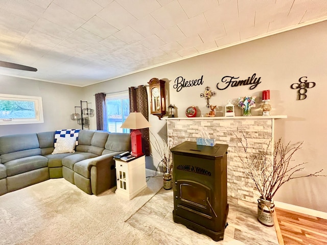 living room with wood-type flooring, a wood stove, and ornamental molding