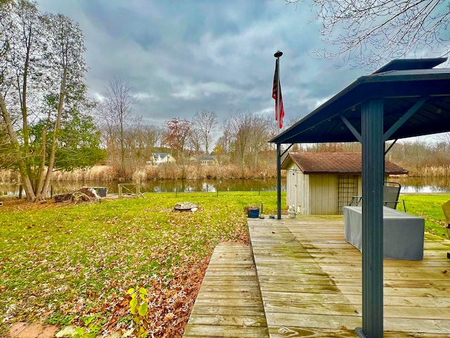 wooden terrace with a gazebo, a water view, and a lawn