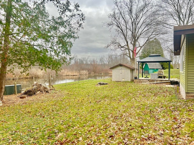 view of yard featuring a gazebo, a water view, and a shed