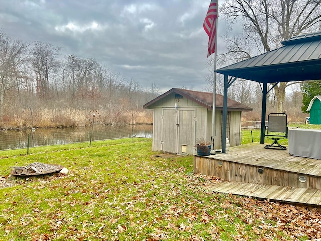 view of yard featuring a deck with water view and a storage unit