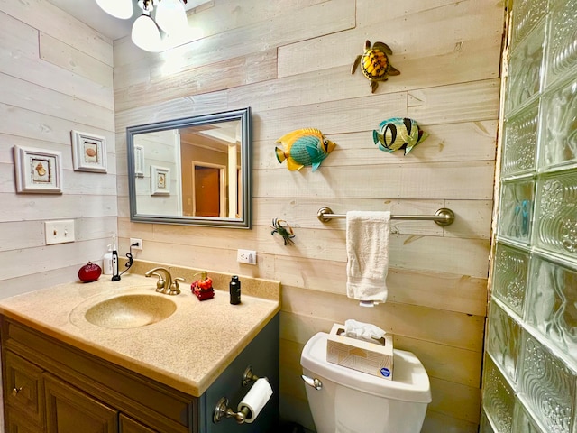 bathroom featuring wood walls, vanity, and toilet