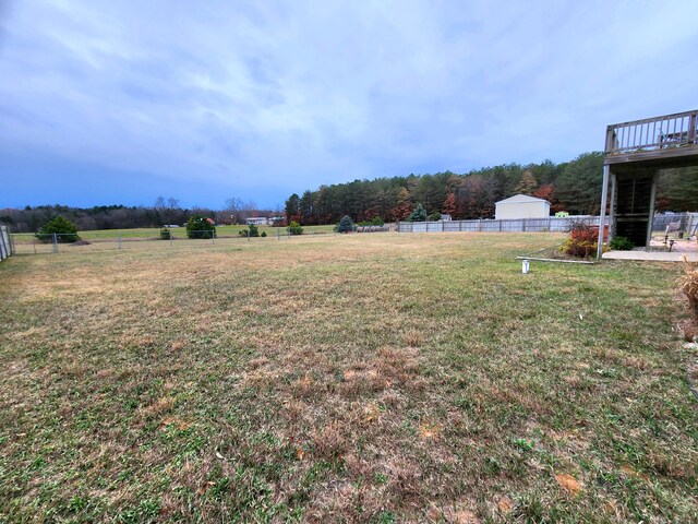 view of yard with a rural view, a garage, an outdoor structure, and a deck