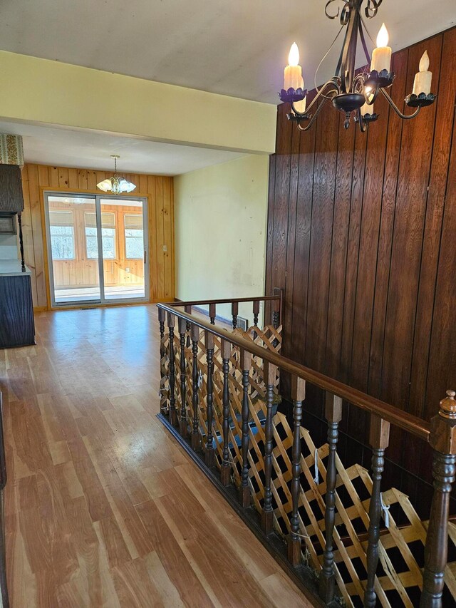 stairway with wood walls, hardwood / wood-style floors, and a notable chandelier