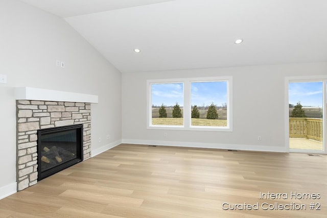 unfurnished living room featuring a stone fireplace, recessed lighting, baseboards, vaulted ceiling, and light wood finished floors