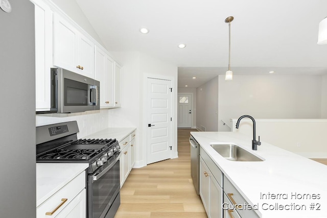 kitchen featuring white cabinets, stainless steel appliances, light wood-type flooring, a sink, and recessed lighting