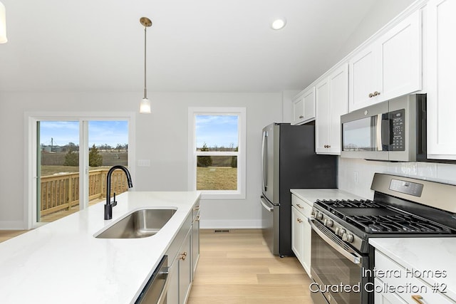 kitchen with light countertops, appliances with stainless steel finishes, a sink, and a healthy amount of sunlight