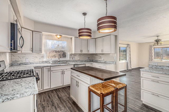 kitchen featuring hanging light fixtures, ceiling fan, a wealth of natural light, and sink