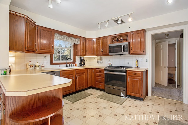 kitchen featuring kitchen peninsula, appliances with stainless steel finishes, tasteful backsplash, and sink