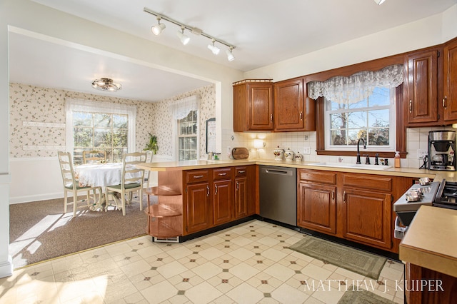 kitchen featuring dishwasher, sink, tasteful backsplash, kitchen peninsula, and light carpet